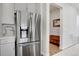 Modern kitchen with a stainless steel refrigerator, light grey cabinetry, and views into an entry hallway at 8211 Monte Vista Cir, Littleton, CO 80125