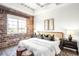 Comfortable bedroom features a cozy bed, exposed brick wall, and natural light for a serene and restful space at 1435 Wazee St # 305, Denver, CO 80202