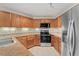 Kitchen area boasting wood cabinetry, stainless appliances, granite counters, and tile flooring at 8623 E Dry Creek Rd # 423, Englewood, CO 80112