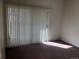 An empty carpeted bedroom shows a sliding glass door and vertical blinds for privacy at 9913 E Carolina Cir # 203, Denver, CO 80247