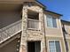 View of condo building with stone facade and outdoor access stairs and balconies on a sunny day at 9913 E Carolina Cir # 203, Denver, CO 80247