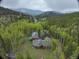An aerial view showcasing the home nestled in the forest and surrounding mountains at 2720 S Spring Gulch Rd, Idaho Springs, CO 80452
