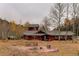 Charming home exterior with wood siding, mature trees, and a welcoming outdoor seating area with a fire pit at 2720 S Spring Gulch Rd, Idaho Springs, CO 80452