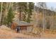 An outbuilding for storage is nestled in a wooded area of the property, adjacent to a small garden at 2720 S Spring Gulch Rd, Idaho Springs, CO 80452
