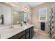 Bathroom featuring a double sink vanity, ample lighting, and a shower-tub combo with stylish curtain at 398 Midden Pl, Castle Rock, CO 80104
