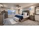 Main bedroom featuring king bed, tray ceiling, windows, ceiling fan, and neutral color scheme at 4965 Malaya St, Denver, CO 80249