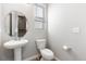 Clean, minimalist half-bathroom with pedestal sink and round mirror, offering a functional space at 23576 E 5Th Pl, Aurora, CO 80018