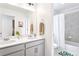 Bathroom with double vanity, framed mirror, tiled shower/tub, and colorful decorative accents at 8057 Monte Vista Cir, Littleton, CO 80125