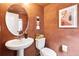 Stylish half-bathroom with decorative accents, a pedestal sink, and an artistic, warm color scheme at 8057 Monte Vista Cir, Littleton, CO 80125