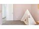 A cozy bedroom with a unique teepee, soft pink walls, and comfortable carpet at 8057 Monte Vista Cir, Littleton, CO 80125