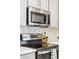 Close up of stainless steel appliances, marble backsplash and grey cabinetry in a modern kitchen setting at 8057 Monte Vista Cir, Littleton, CO 80125