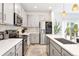 Well-lit kitchen with stainless steel appliances, gray cabinets, and a kitchen island overlooking the living area at 8057 Monte Vista Cir, Littleton, CO 80125