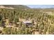 Aerial view of a luxurious home surrounded by beautiful trees and mountain views in the background at 20496 Stonewood Trl, Morrison, CO 80465