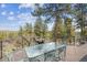 Large back deck with an outdoor dining area and seating offers scenic wooded views at 20496 Stonewood Trl, Morrison, CO 80465