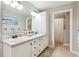 Well-lit bathroom with double sinks, a white tiled counter, and shower with a curtain at 20496 Stonewood Trl, Morrison, CO 80465