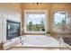 Luxurious soaking tub with window view, fireplace, and clear glass shower with tiled surround at 20496 Stonewood Trl, Morrison, CO 80465