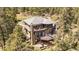 Exterior aerial view of a two-story home featuring multiple decks and surrounded by lush trees at 20496 Stonewood Trl, Morrison, CO 80465