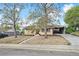 Inviting home exterior with mature trees, rock landscaping, and a convenient carport at 6953 Elati Way, Denver, CO 80221