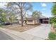 Exterior of home featuring driveway leading to an attached carport, mature trees, and rock landscaping at 6953 Elati Way, Denver, CO 80221