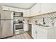 Bright, modern kitchen features stainless appliances, white cabinets, quartz counters, and stylish backsplash at 6953 Elati Way, Denver, CO 80221