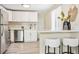 Bright and modern kitchen featuring white cabinetry, stainless steel appliances, and stylish bar seating at 6953 Elati Way, Denver, CO 80221