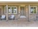 Inviting front porch with seating area, a porch swing, brick facade and charming exterior details at 904 Fieldstone Pl, Highlands Ranch, CO 80126