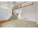 Bright foyer featuring a staircase with wood railing and neutral carpet throughout the main level at 3087 Deer Creek Trl, Highlands Ranch, CO 80129