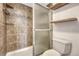 A bathroom with a tiled shower, a wooden floating shelf, and modern fixtures, offering a clean and functional space at 2525 S Dayton Way # 2209, Denver, CO 80231