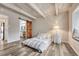 Bedroom featuring exposed beam ceiling, wood floors, sliding barn door to the ensuite bath, and a cozy window seat at 2525 S Dayton Way # 2209, Denver, CO 80231