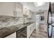 Well-lit kitchen featuring stainless steel appliances, black granite counters, and a neutral colored tile backsplash at 2525 S Dayton Way # 2209, Denver, CO 80231
