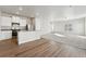Open-concept living area featuring wood floors transitioning to carpet, with a modern kitchen and bright natural light at 3004 Oxley St, Strasburg, CO 80136