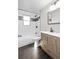 Updated bathroom featuring a tub with white tile surround and a modern wood vanity with solid surface countertop at 1862 Queens Dr, Longmont, CO 80501