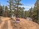 Secluded mountain home with dirt driveway, tall trees, and visible real estate signage at 26349 Pleasant Park Rd, Conifer, CO 80433