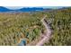 Serene aerial shot of houses surrounded by dense forest and a winding road, creating a peaceful, secluded environment at 9590 S Warhawk Rd, Conifer, CO 80433