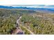 Breathtaking aerial view of homes nestled in a lush, green forest landscape against a backdrop of majestic mountains at 9590 S Warhawk Rd, Conifer, CO 80433