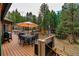 Inviting outdoor deck with a dining table, chairs, umbrella, and serene views of the forest at 9590 S Warhawk Rd, Conifer, CO 80433