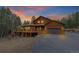 Beautiful wood-clad home featuring a spacious deck and attached garage, set against a picturesque sunset sky at 9590 S Warhawk Rd, Conifer, CO 80433