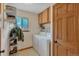 Well-lit laundry room with a washer, dryer, storage shelf, cabinets and a window at 9590 S Warhawk Rd, Conifer, CO 80433