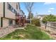 Expansive backyard with grass area, rock feature, and stairs to the home's upper-level deck at 12551 W 84Th Cir, Arvada, CO 80005