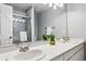 A clean, bright bathroom featuring a double vanity, light countertops, and a shower with glass door at 12551 W 84Th Cir, Arvada, CO 80005