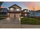 Charming two-story home with a well-manicured lawn and a two-car garage at twilight at 12551 W 84Th Cir, Arvada, CO 80005