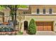 Inviting two-story home with a light yellow stucco exterior, arched windows, a wood garage door, and mature landscaping at 100 S University Blvd # 4, Denver, CO 80209