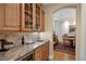 Convenient wet bar area with granite countertops, custom cabinetry, and beverage fridge at 100 S University Blvd # 4, Denver, CO 80209