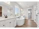 Bright bathroom featuring dual vanities, a soaking tub and a shower with glass doors at 1784 Morgan Dr, Erie, CO 80516