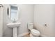 Modern powder room with a pedestal sink, round mirror, and sleek fixtures at 1784 Morgan Dr, Erie, CO 80516