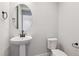 Classic half-bathroom featuring a pedestal sink, round mirror, and modern fixtures at 1784 Morgan Dr, Erie, CO 80516
