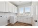 Laundry room featuring bright lighting, white cabinetry, a utility sink, and wood-look floors at 1784 Morgan Dr, Erie, CO 80516