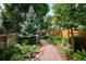 A winding gravel path is surrounded by lush landscaping and mature trees at 1563 S Trenton Ct, Denver, CO 80231