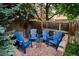 Charming backyard patio with four blue chairs and a small table offers an inviting outdoor space at 1563 S Trenton Ct, Denver, CO 80231