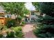 Exterior of home showcasing a well-manicured backyard with a deck, gravel path, and mature trees at 1563 S Trenton Ct, Denver, CO 80231